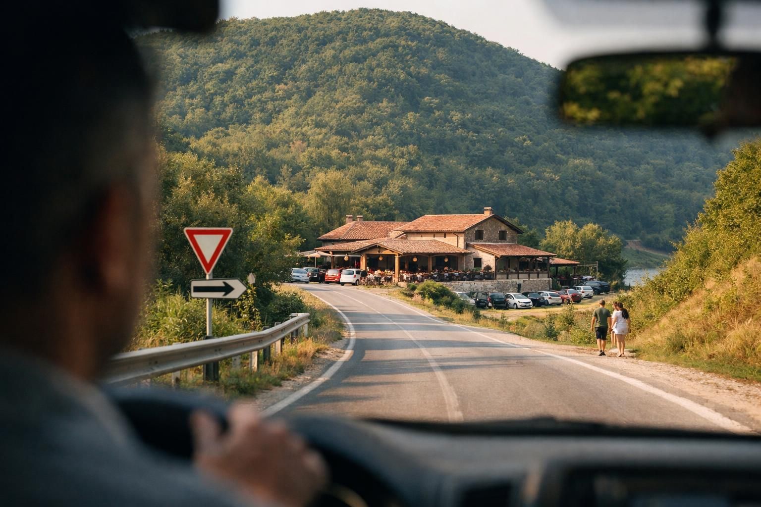 View from car toward roadside restaurant and forested hill